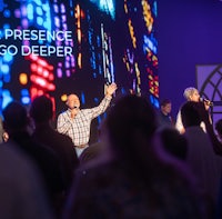 a group of people singing in front of a large screen