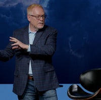 a man is standing in front of a blue sky with clouds