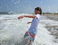 a young boy splashing in the water on the beach