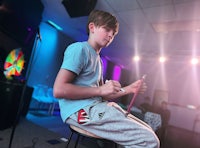 a young boy sitting on a stool in a room with lights