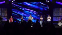 a group of people standing on stage in front of a large screen