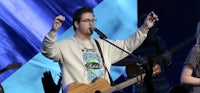 a man singing with his hands up in front of a group of people