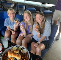 three girls sitting on a couch with food on their laps